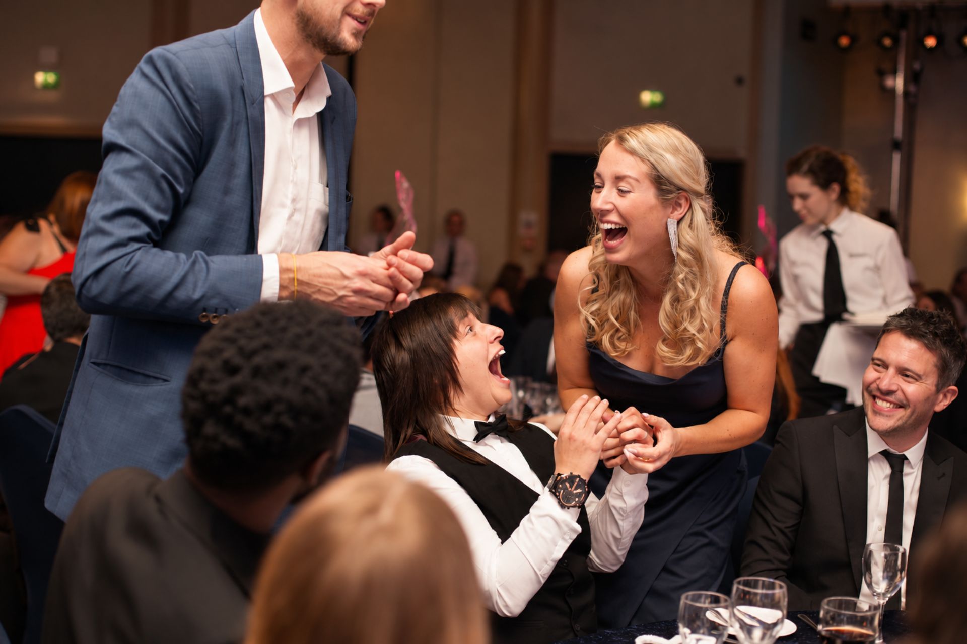 Guests at a dinner table laughing during close-up magic