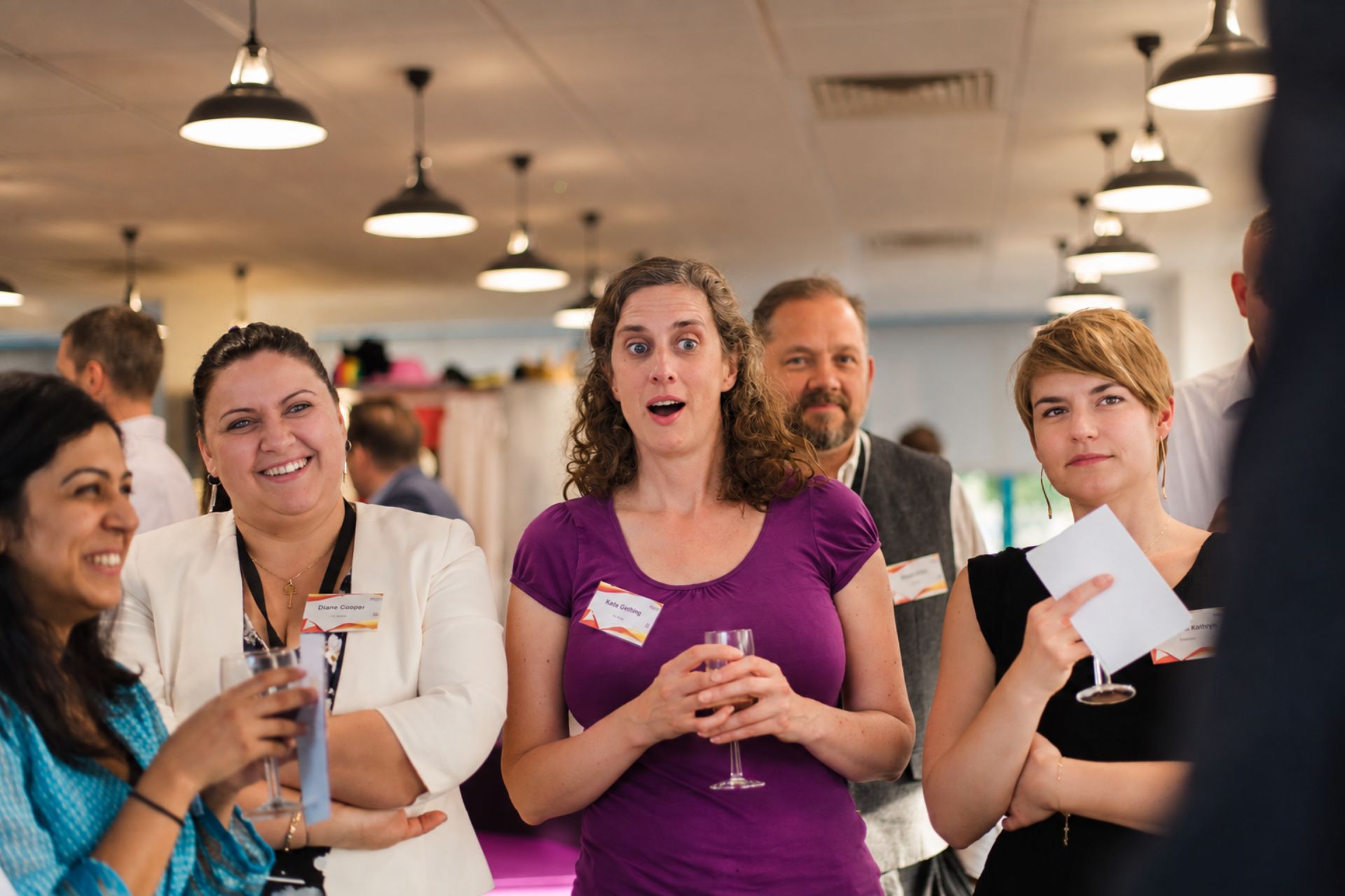 Guests at a drinks reception reacting to a card trick